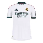 Real Madrid 26/27 Home Player Version football jersey in white with dark green collar and sleeve details, pink adidas shoulder stripes, and premium slim-fit design displayed on a plain background.